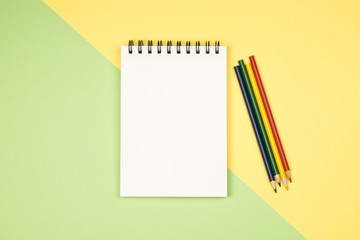 Top view of blank notebook page with colored pencils