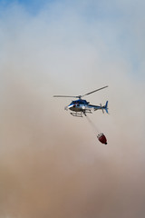 Fototapeta na wymiar hélicoptère au dessus d'un feu avec un sac d'eau