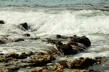 Beautiful grey sea stormy waves splash against black stony shore