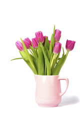 a pretty arrangement of a bouquet bunch purple tulips in a pink vase isolated on white