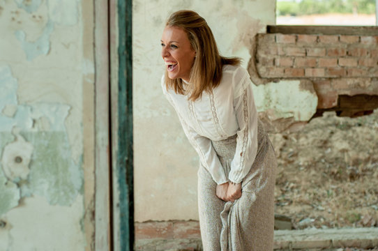 Mujer en habitacion derruida riendo