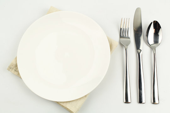 white plate on white background decoration with spoon and fork