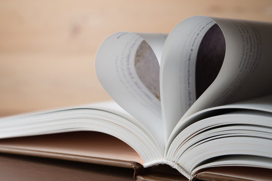 Concept for valentine or love - Open a book is placed on a heart-shaped books placed with calendar showing 14th of february in the backdrop wooden.