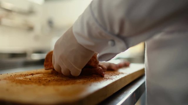Closeup of professional chef man prepare meat ribs with spice on cutting board at restaurant kitchen