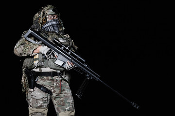Army sniper with big rifle standing on black background