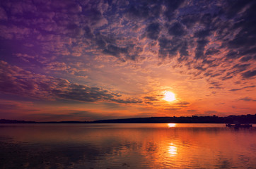 Fototapeta na wymiar majestic sunset at the lake. colorful clouds in the sky gloving in sunlight.