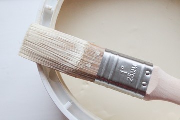 Used paintbrush resting on an open tin of paint