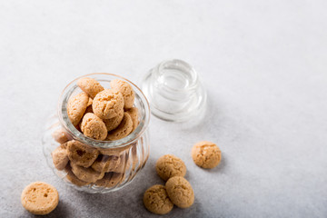 Amaretti cookies in glass pot on light gray background with copy space. High angle view