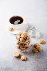 Amaretti cookies in glass pot with white cup of coffee on light gray background with copy space. High angle view