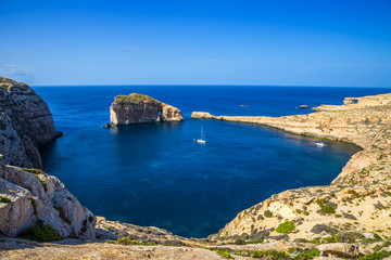 Gozo, Malta - Panoramic skyline view of Dwejra bay with Fungus Rock, Azure Window and sailboat on a nice hot summer day