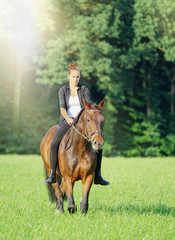 Junge Frau reitet mit ihrem Pferd durch Wald und Flur