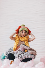 Beautiful girl sitting on the floor with knitted clothing