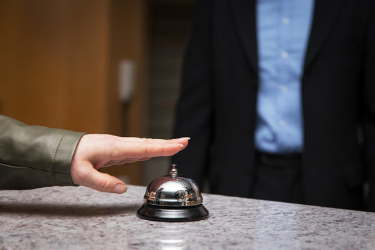 Frau klingelt auf Glocke von Rezeption, Information und Service im Hotel