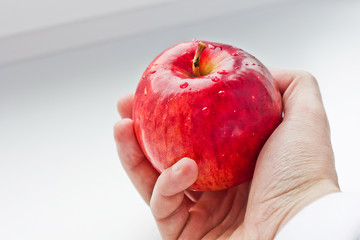 Red apple in the hand on a white background.