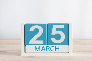 March 25th. Day 25 of month, daily calendar on wooden table background. Spring time, empty space for text.
