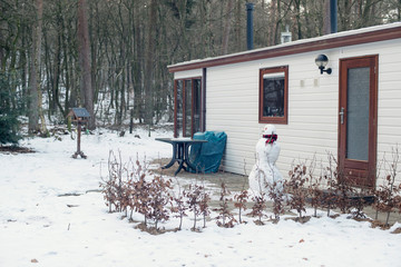 Snowman standing in front of mobile home.