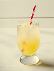 Ice lemonade with cocktail tube in glass, on white background.