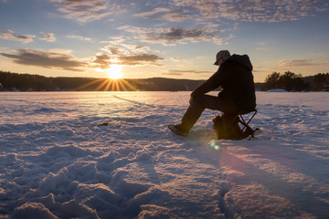 Ice fishing on a lake in Norway at sunset. - Powered by Adobe