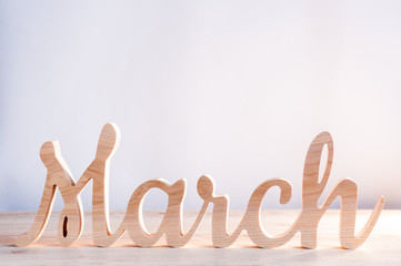 Word month of MARCH carved in wood with light background. Beginning of springtime. Spring hello concept © bychykhin