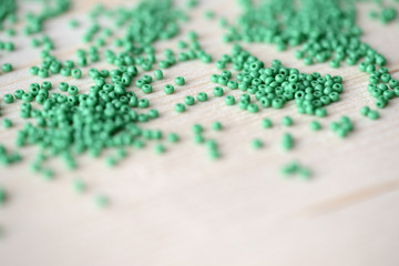 Scattered seed beads of green color on the wooden background