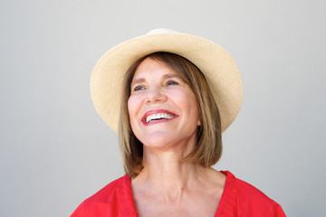 beautiful older woman laughing with hat against gray wall