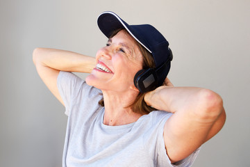 Portrait of smiling older woman with hands behind head listening to music with headphones