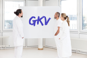 Fototapeta premium Mediziner stehen vor weißer Tafel, GKV oder gesetzlicher Krankenversicherung
