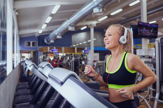 Sport blonde girl smiling happy on the treadmill in the gym.