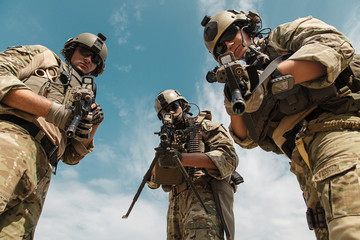 US Army Rangers pointing weapons to the camera detaining person. Low angle view