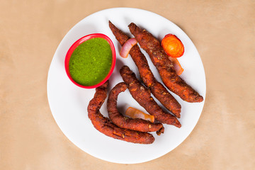Chicken fingers - a spicy Indian dish served with green coriander chutney clicked on brown background available with clipping path