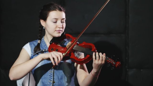 4k Young woman playing on violin in a studio. Black backgraund
