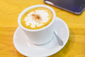 hot coffee on the table and smartphone on background