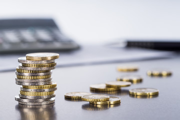 Ein Stapel Euromünzen, Stift und Taschenrechner