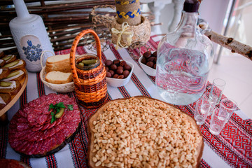 Bottle with vodka and plates with pickled vegetables and meat stand on the table