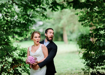 Funny newlyweds scream standing in the arch of greenery