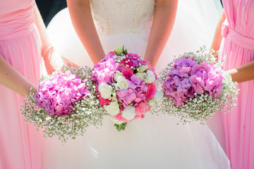 Bride and bridesmaids hold their hands with wedding bouquets together