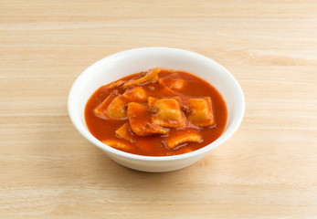 Bowl of ravioli on a wood table side view.