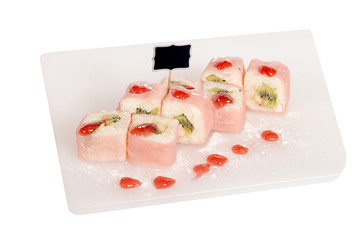 Sweet sushi for a children's menu with fruit and syrup on white plate with isolated background