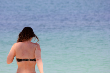 Fototapeta premium European tourists girl in a bikini on the beach with ocean background. 