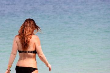 Obraz premium European tourists girl in a bikini on the beach with ocean background. 