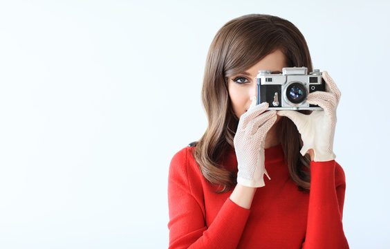Retro style portrait of young beautiful woman taking photo with camera