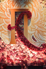 Golden initials and red and pink chrysanthemums decorate the wall