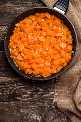 Roasted pumpkin on the pan over dark wooden background. Top view.