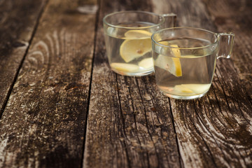 Detox water with lemon and ginger in two glass cups.