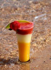 Cocktail in a glass with strawberries, mango, guava on the seafront