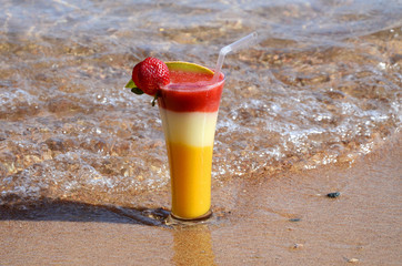 Cocktail in a glass with strawberries, mango, guava on the seafront