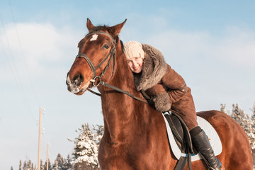 Fototapeta premium Woman in brown dress and brown horse in a winter