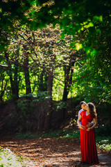 The husband  with pregnant wife embracing in the forest