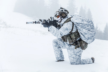 Winter arctic mountains warfare. Action in cold conditions. Trooper with weapons in forest...