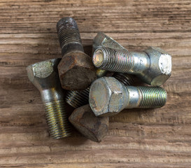 Old rusty and new bolts on wooden background